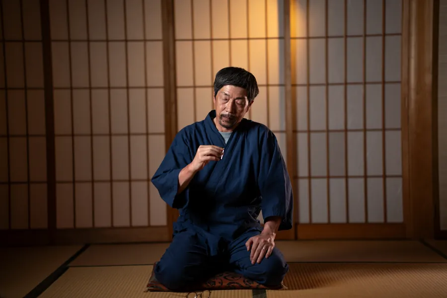 Our craftsman kneeling on a tatami floor, holding a seal