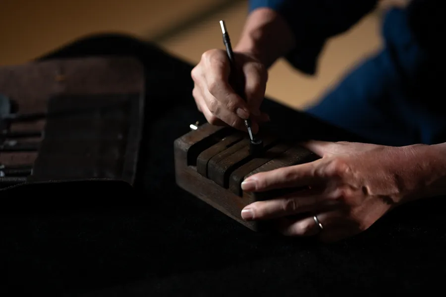 Close-up of hands carving a seal held in a wooden clamp