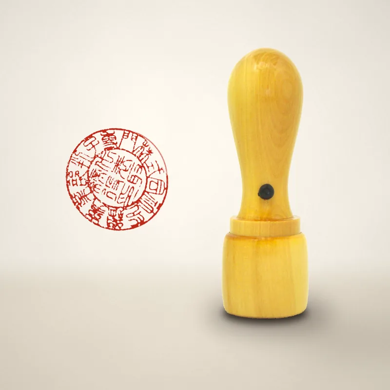 A round company seal in akane wood with a cap, next to a sample impression