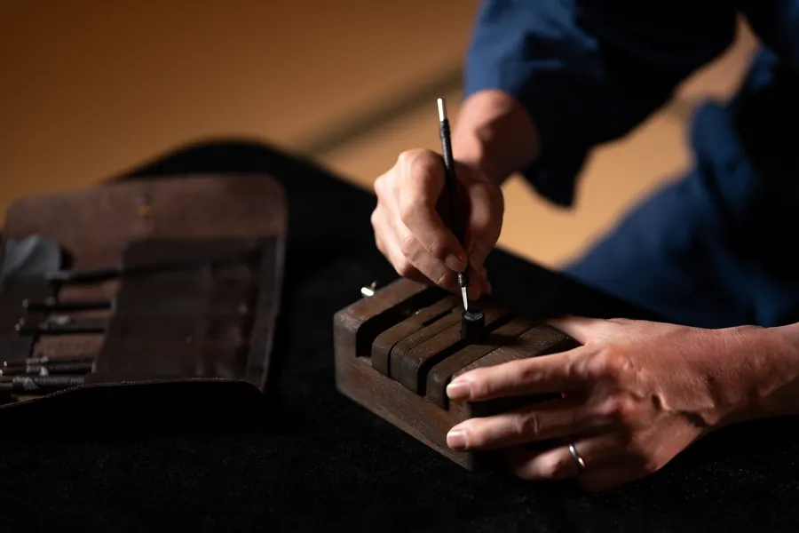 The craftsman's hands finishing the face of a seal held in a wooden clamp