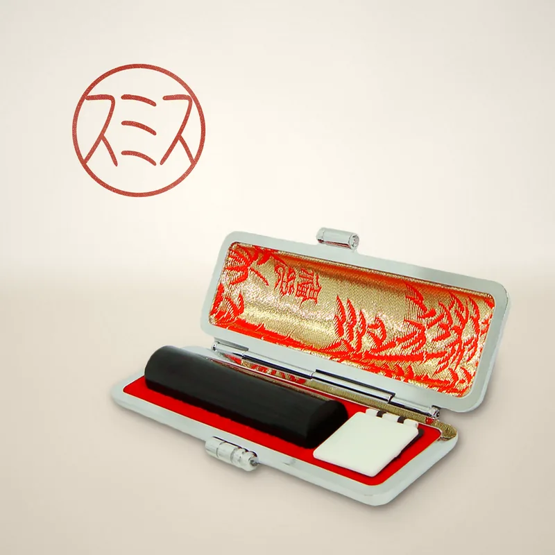 Bank seal in black buffalo horn inside its open case, with a red sample impression reading スミス in katakana
