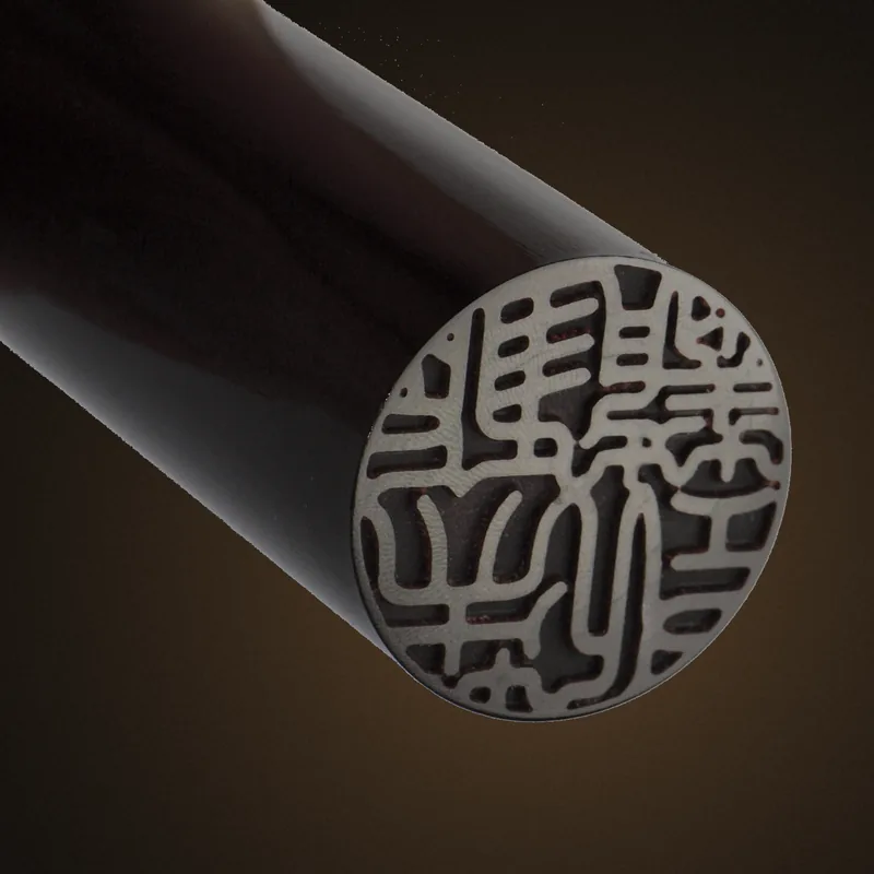 Close-up of a carved seal face in black buffalo horn, showing fine seal-script lines