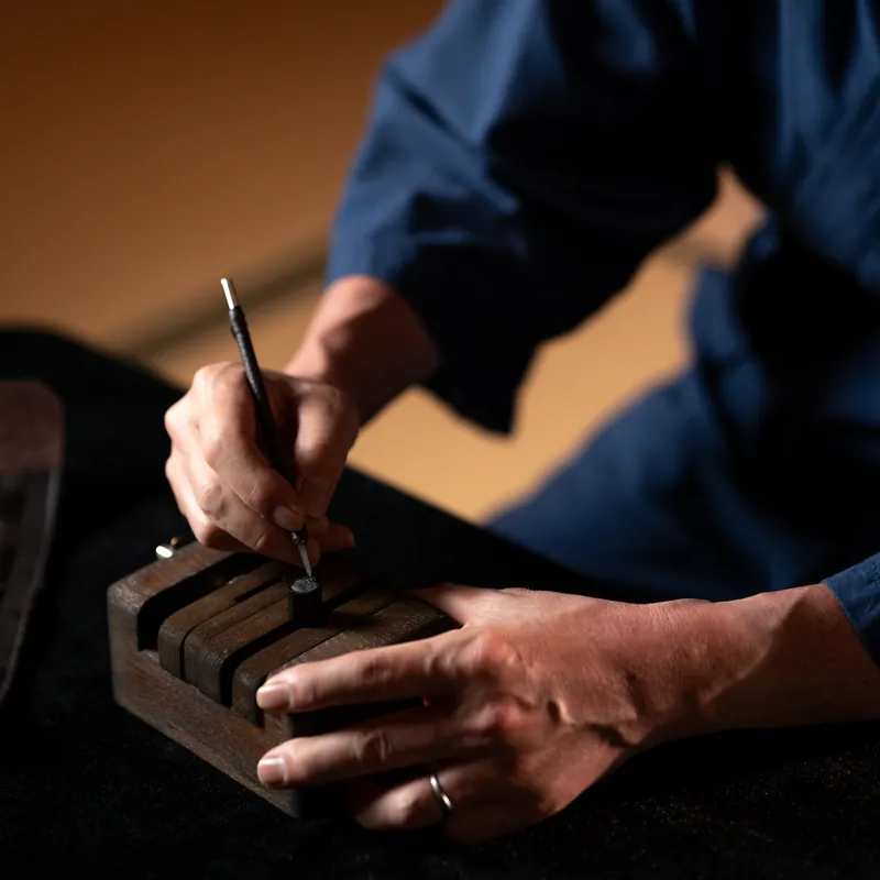 The craftsman's hands finishing the face of a seal held in a wooden clamp